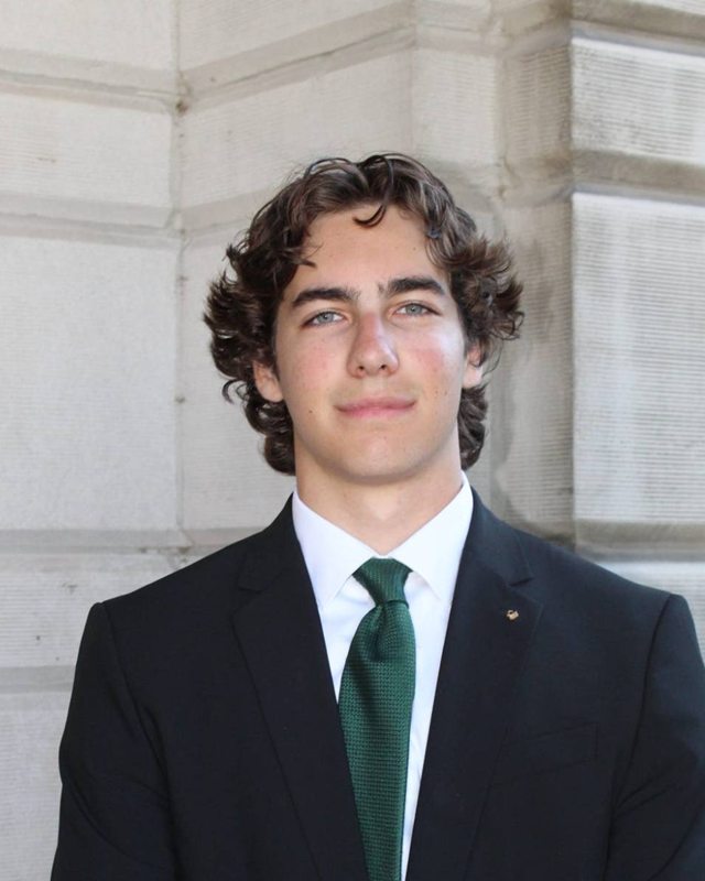 Justin M. Lutz in a dark suit and green tie